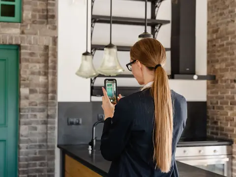 Taking a phone photo of a kitchen with a brick wall and green doors