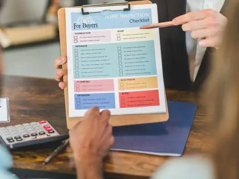 Going over a home buyer checklist on a clipboard at a desk with a calculator