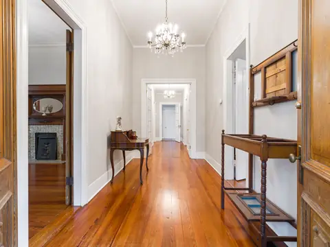 A bright front hallway with polished wood floors, open doors and a chandelier