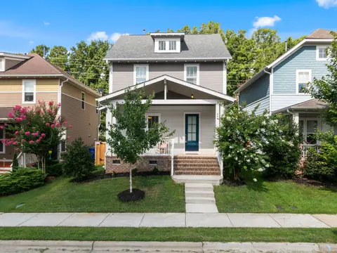 A white two-story home with a porch and steps up from the sidewalk