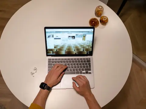 Working on a laptop at a round white table, seen from above