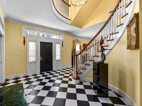 A grand entry hall with a curved staircase and a black and white checkered floor