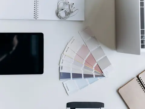 A notebook, a tablet and a fan of color samples on a white desk