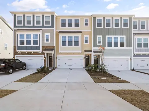 A row of three-story townhomes in pale colors with white garage doors