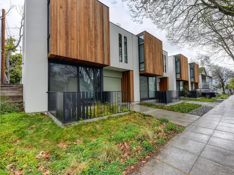 Modern homes with wood-clad upper floors along a tree-lined sidewalk