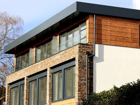A modern home with a stone and wood front and wide windows