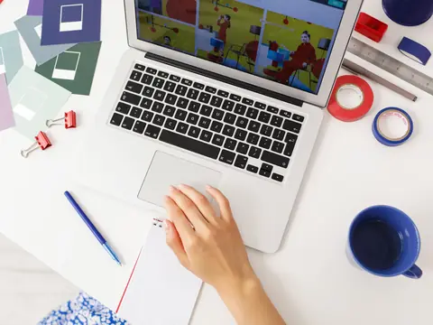 A laptop, a notepad and a blue mug on a bright desk